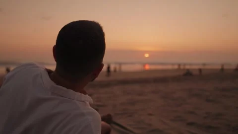 Man Sitting on Beach at Sunset and Enjoying the Ocean View in Seminyak Bali Stock Footage 346293677