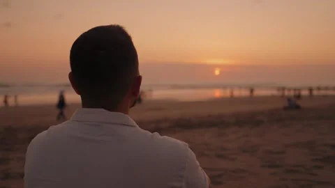 Man Sitting on Beach at Sunset and Enjoying the Ocean View in Seminyak Bali Stock Footage 346293731