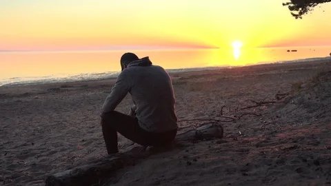 The man sitting on the beach at sunset Stock Footage 129640653