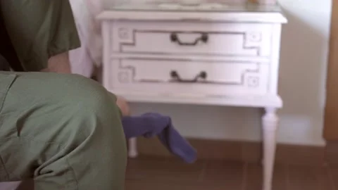 Man sitting on bed and putting on socks in bedroom Stock Footage 132285712