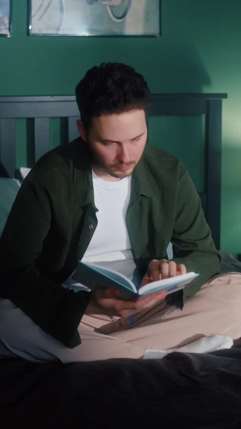 Man sitting on bed and reading book Video stock 322569373
