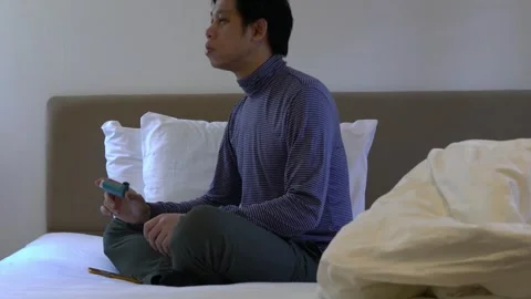A man is sitting on a bed and using An inhaler for asthma medicine Stock Footage 314611722