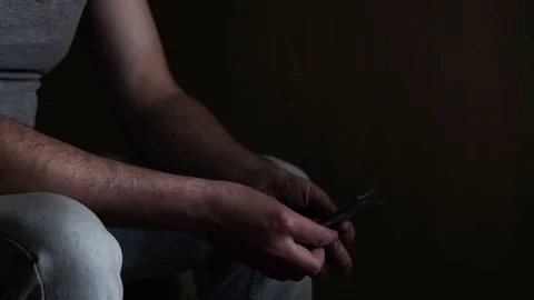 Man sitting on a bed in a dark room counting money, american dollars banknotes Stock Footage 129820759