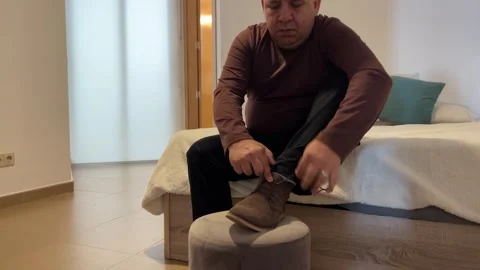 Man sitting on bed finishing getting dressed and putting on shoes Stock Footage 333406239
