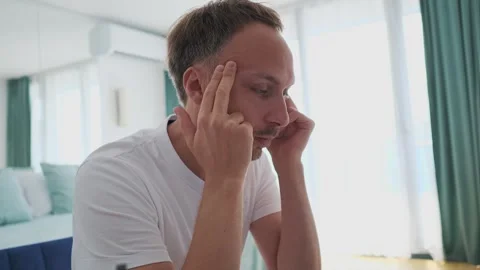 Man is sitting on bed with his hands on his face 스톡 동영상 265235947