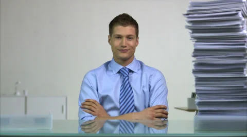 Man sitting behind a desk, using his finger to decrease the pile of paper beside Stock Footage 51818107