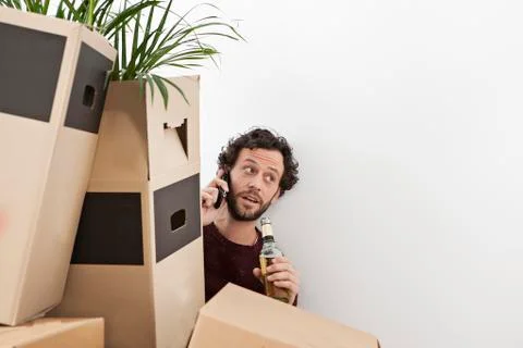 Man sitting behind stack of cardboard boxes and talking on mobile phone Stock Photos