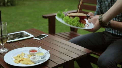 Man sitting behind the table and texting messages. Waitress brings him hamburger Video stock 51441375