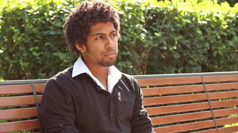 A man sitting on a  bench  and looking at people. Stock Footage 55597005