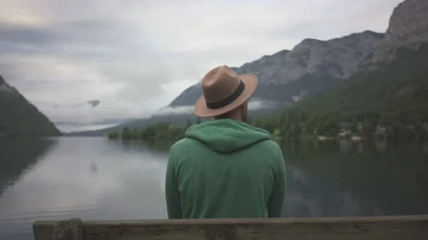 Man sitting on bench and looking at view of mountain lake Grundlsee in fog Stock Footage 132051673