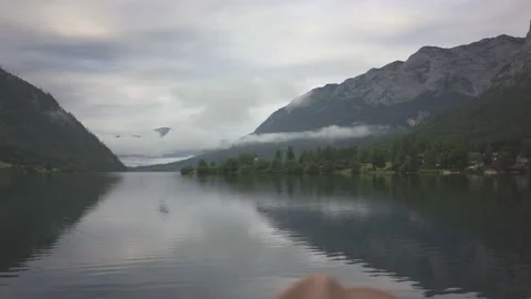 Man sitting on bench and looking at view of mountain lake Grundlsee in fog Stock Footage 132059440
