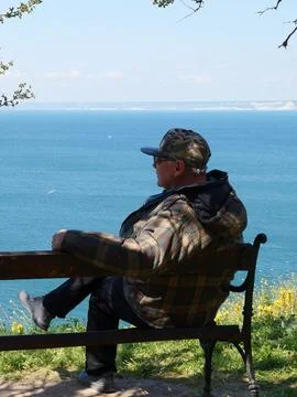 Man sitting on a bench and looking at the sea panorama, rear view Foto stock