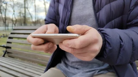 Man sitting on bench and playing game on smartphone 库存影片 215076046