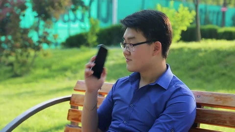 Man sitting on bench and talking on phone, business man in nature Video stock 90284128