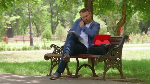 Man Sitting on the Bench and Working Outdoors. Vidéo 132010171