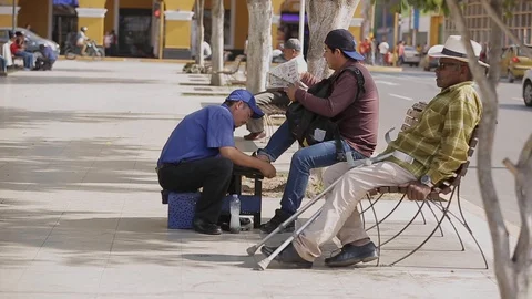 A man is sitting on a bench. cleans shoes.  on the street. Stock Footage 128410190