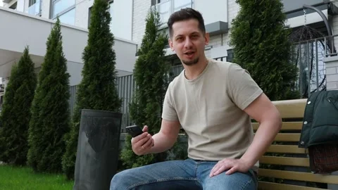 Man Sitting on Bench in Front of Building Vídeos de archivo 274150201