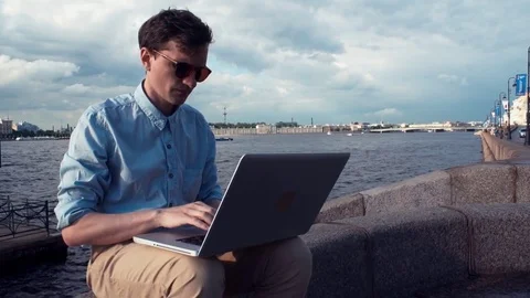 Man sitting on bench with laptop receiving good news and celebrating success Stock Footage 77167364