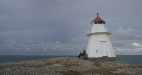 Man sitting on bench by a lighthouse. Stock-Footage 106120457