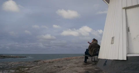 Man sitting on bench by a lighthouse. Stock Footage 106120568