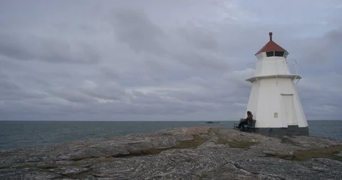 Man sitting on bench by a lighthouse. Stock-Footage 106121180