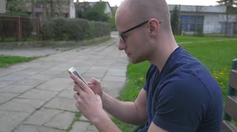 Man sitting on the bench with mobile phone. He is serious. Stock Footage 62519255