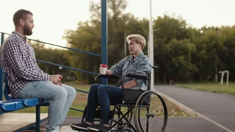 Man is sitting on bench next to disabled woman in wheelchair on field. Married Stock Footage 160932479