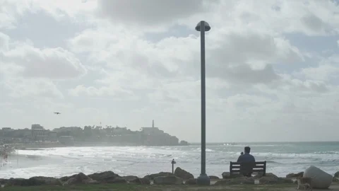 Man sitting on bench with old Jaffa in background Stock Footage 100704600
