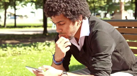 Man sitting on the bench in the park and looking in the phone. Stock Footage 55597798