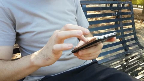 Man sitting on a bench scrolling phone message Stock Footage 139041820