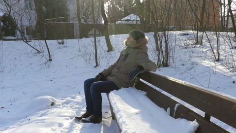 Man sitting on a bench with snow in winter Stock Footage 71754950