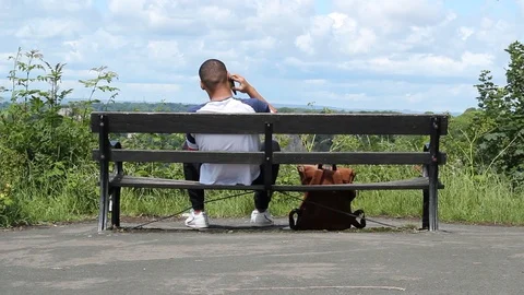 Man sitting on the bench taking a phone call 스톡 동영상 111154459