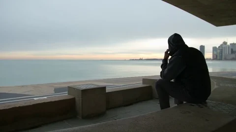 Man is sitting on the bench talking on the phone and looking at the sea Stock-Footage 82652076