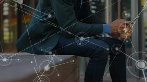 Man sitting on bench tapping phone and sparking node overlay growing across Stock Footage 321979354