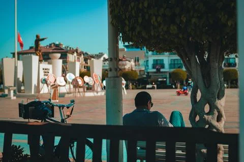 Man Sitting on a Bench under a Tree with His Bicycle Foto stock