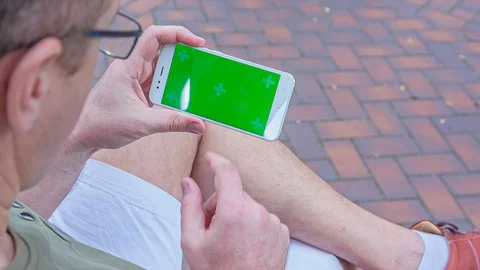 Man sitting on the bench uses SmartPhone with green screen 1 Stock Footage 116404050