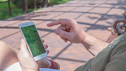 Man sitting on the bench uses SmartPhone with green screen 3 Stock Footage 116404354