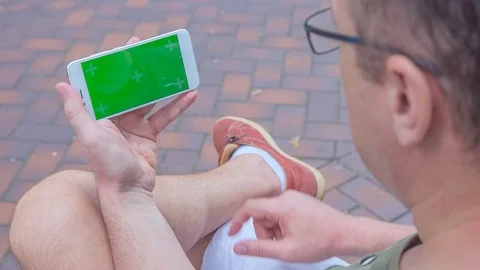 Man sitting on the bench uses SmartPhone with green screen 2 Stock Footage 116404382