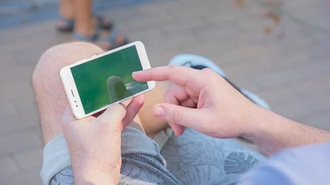 Man sitting on the bench uses SmartPhone with green screen 4 Stock Footage 116404390