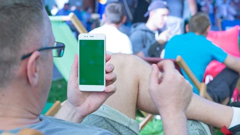 Man sitting on the bench uses SmartPhone with green screen 7 Stock Footage 116405737