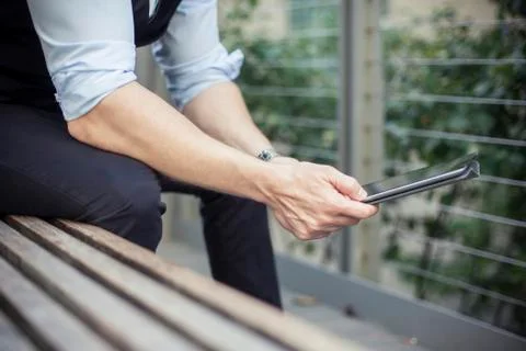 Man sitting on bench, using digital tablet, cropped Stock Photos