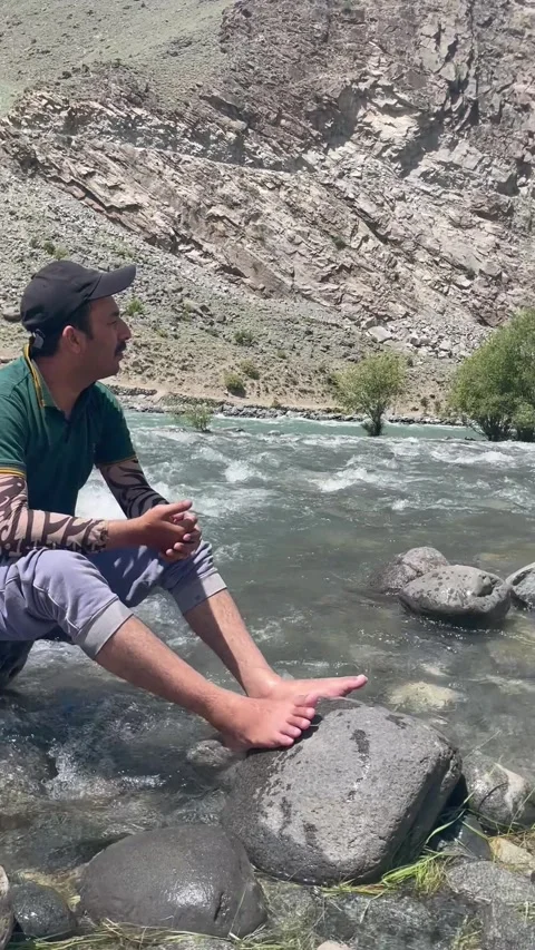 Man Sitting Beside Indus River in Skardu Pakistan with Mountain Landscape 스톡 동영상 343616861