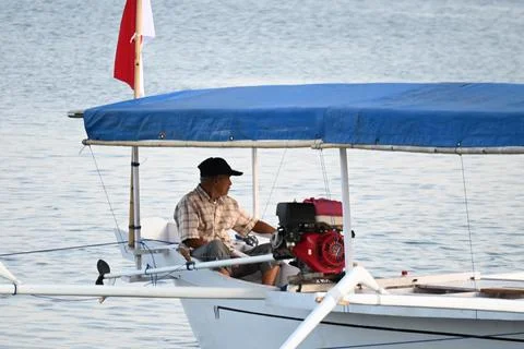 A man is sitting in a boat with a red engine 스톡 사진