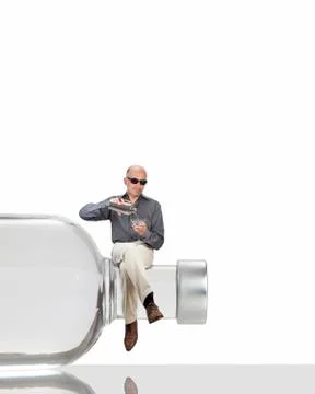 Man sitting on a bottle serving himself a martini Stock Photos