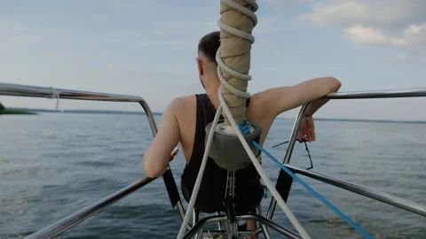 A man is sitting on the bow of a yacht, drinking wine and enjoying the evening Stock Footage 201192404