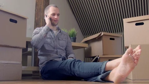Man sitting by boxes talking on cell phone Stock Footage 72231032