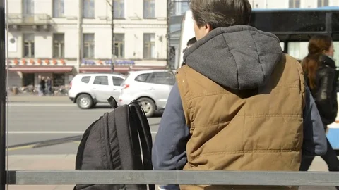 Man sitting at the bus stop and using the phone 動画素材 75418306