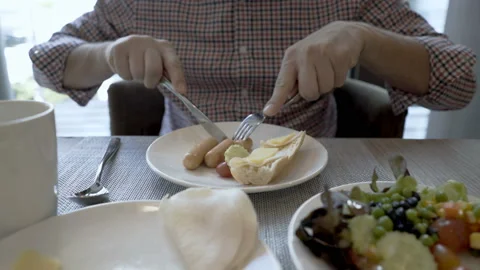 Man sitting in the cafe and eating sausages for breakfast  Stock Footage 88436233