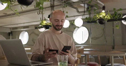 Man sitting at cafe and using credit card with smartphone Stock Footage 159083750