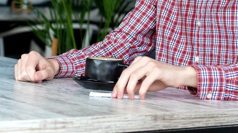 The man is sitting in a cafe with a cup of coffee. sugar stick in hand Stock Footage 111728769
